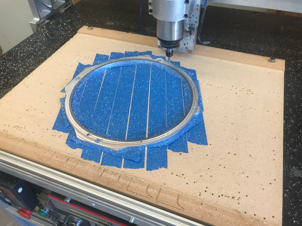CNC mill cutting a circular aluminum part on a taped fixture